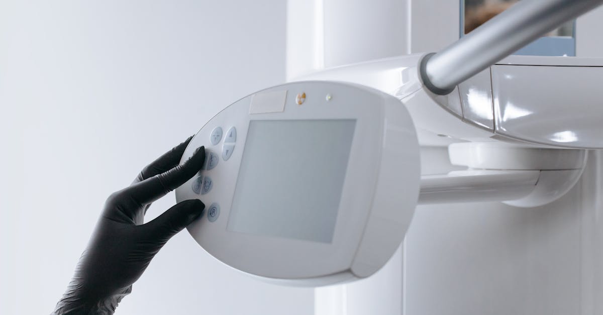 close up of gloved hand operating dental x ray machine in clinical setting